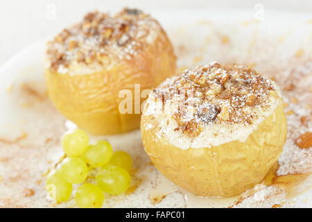 Les pommes cuite au four avec du fromage cottage et raisins secs, décoré avec des noix, de la cannelle et de sucre en poudre Banque D'Images