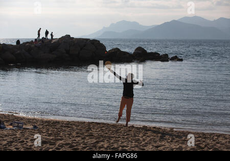 Les amateurs de soleil d'hiver bénéficiant d'une journée ensoleillée sur la Rviera beach, boulevard du Midi Jean Hibert, Cannes, Côte d'Azur, France Banque D'Images