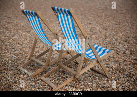 Bleu-et-blanc à rayures transats sur la plage de Brighton. Banque D'Images