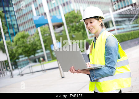 Young construction worker holding her laptop Banque D'Images