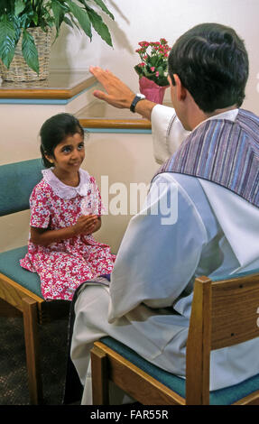 Prêtre blanc avec sa main soulève bénit 6 an ans girl wearing pink floral dress lors du rapprochement MR ©Myrleen Pearson.......Ferguson Cate Banque D'Images