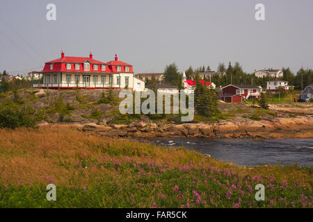 Ville pittoresque Johann Beetz sur côte avec bras de mer visible. Au nord-est du Québec. Feu violet fleurs mauvaises herbes en premier plan. Banque D'Images