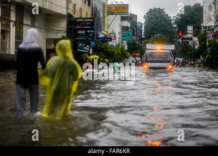 Enfants marchant dans les eaux de crue dans une rue inondée lors d'une forte pluie dans le centre-ville de Jakarta, en Indonésie. Banque D'Images