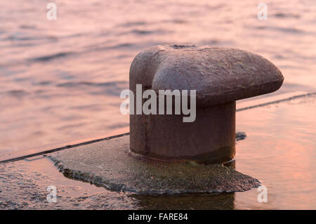 Gros plan sur un bollard rouillée dans un bassin, coucher de la lumière Banque D'Images