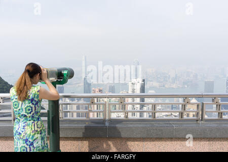 Une femme à la recherche au moyen d'un télescope à Hong Kong Banque D'Images