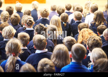 Groupe d'enfants assis dans une salle d'école au cours d'une assemblée générale à l'éducation une petite école britannique Banque D'Images