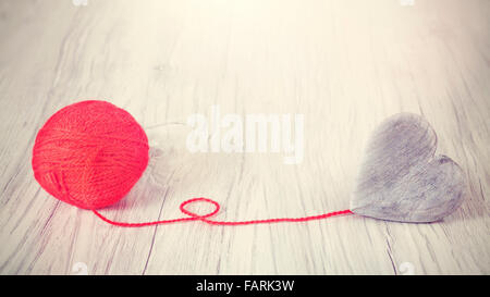 Coeur en bois relié au fil rouge, concept photo. Banque D'Images