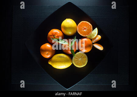 Juicy mûr de mandarine, d'orange et mandarine avec des feuilles de citron sur la plaque noire. Banque D'Images