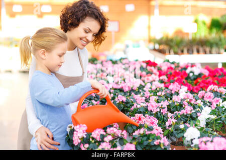 Petite fille et arrosage des fleurs fleuriste. Banque D'Images