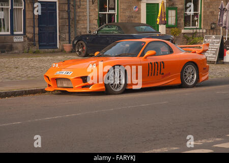 Mazda RX7 de couleur orange sports voiture garée à l'extérieur de librairie dans le village de Middleton-in-Teesdale,fr,Durham Angleterre Banque D'Images