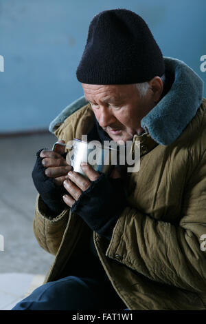 Homeless man holding sa tasse en fer. Banque D'Images