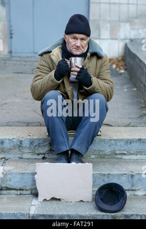 Homeless man holding sa tasse en fer. Banque D'Images