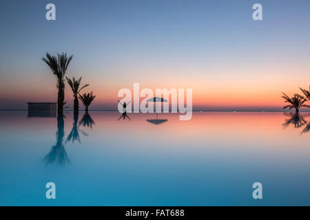 Chypre, Paphos, Paphos, Roi Evelthon hôtel. Palmtree reflet dans la piscine. Se félicitant de la femme soleil. Banque D'Images