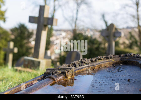 La mise en commun de l'eau sur une pierre tombale tombée. Banque D'Images