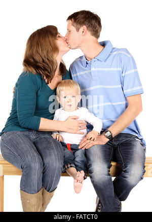 Caucasian family avec papa maman et bébé garçon. Ils sont tous des jeans en denim et assis sur un banc en bois. Les parents sont kiss Banque D'Images