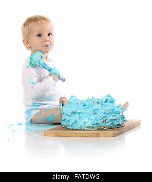 Un petit garçon âgé d'un an brisant une anniversaire glacé bleu gâteau sur une planche de bois. L'image est isolé sur un fond blanc. Banque D'Images