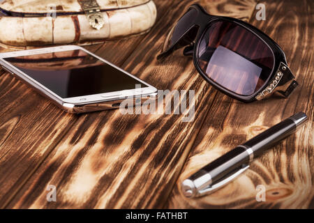Téléphone mobile, pan et lunettes de soleil sur le fond de bois. Banque D'Images