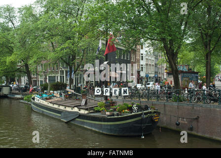 La vieille ville d'Amsterdam, Hollande. House boat / Musée Barge sur un canal et scène de rue avec des vélos et des arbres. Banque D'Images