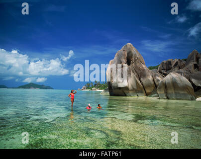 Couple in aqua eaux près de rochers de granit à l'Anse Source d'argent sur l'île de La Digue aux Seychelles Banque D'Images