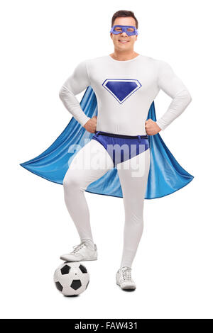 Portrait d'un jeune super héros dans un costume blanc et bleu enjambant un football isolé sur fond blanc Banque D'Images
