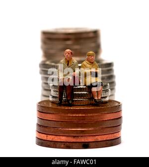 Miniature 2 personnes retraités assis sur des piles de pièces de monnaie britanniques Banque D'Images
