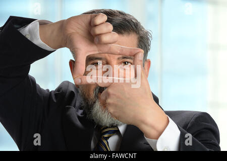 Portrait of Hispanic businessman making cadre avec les mains à l'intérieur de l'environnement de bureau Banque D'Images