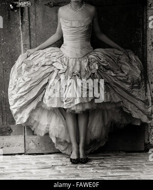 Image en noir et blanc d'une personne dans une robe de mariage à côté d'une porte ancienne. Banque D'Images