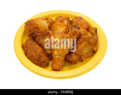 Vue latérale d'une portion de poulet Buffalo wings sur une plaque de papier jaune isolé sur fond blanc. Banque D'Images