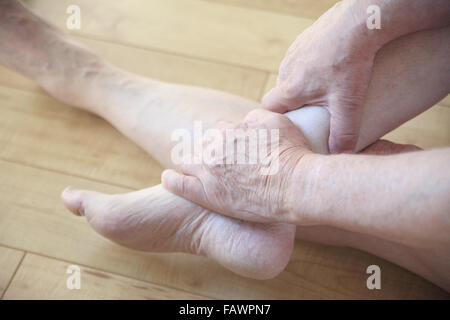 L'homme assis sur le plancher principal est titulaire d'une cheville avec les deux mains. Banque D'Images