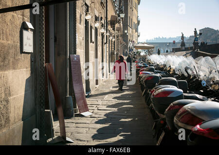 Femme au manteau rouge marchant le long de la rue Lungarno Corsini à Florence, Italie Banque D'Images