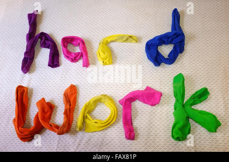 Les mots travail dur fait de chaussettes colorées portant sur une couette. Banque D'Images