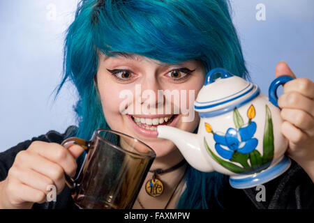 Jeune femme posant avec un drôle de visage et verser le thé. Banque D'Images