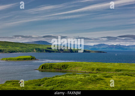 Un petit bâtiment se trouve sur la côte de Sand Point, avec les îles et montagnes en arrière-plan, Sand Point, le sud-ouest de l'Alaska, USA, l'été Banque D'Images