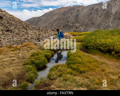 Femme sautille à travers le long de la creek lacs bleus Monte Cristo Gulch trail, montagnes Rocheuses près de Breckenridge, Colorado Banque D'Images