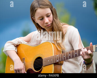 Outdoor portrait of teenage girl playing acoustic guitar Banque D'Images