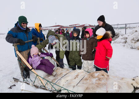 Les enfants de l'école élémentaire portant des engins d'hiver attendre pour monter un traîneau autour de la lagune, Barrow, versant nord, AK, États-Unis d'Arctique, l'hiver Banque D'Images