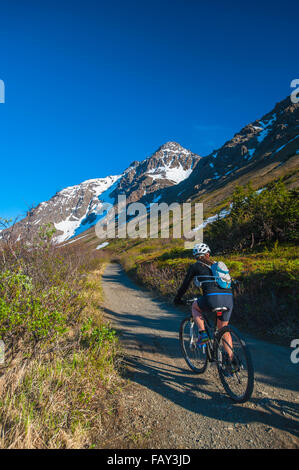 Une femme équitation son vélo au Col Powerline Vallée en parc d'état de Chugach, Southcentral Alaska. Banque D'Images