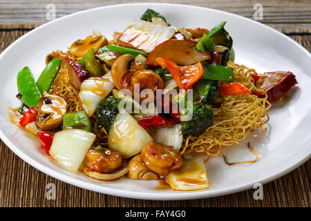 Close up Vue de face d'un nouilles sautées aux crevettes, porc, légumes et sauce en plaque blanche. Banque D'Images