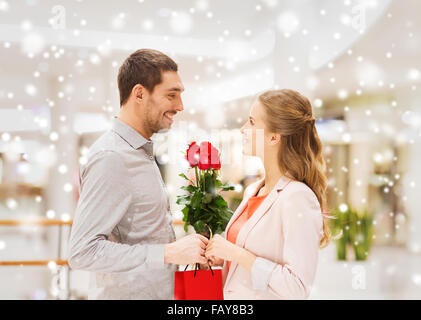 Man giving woman roses rouges et présente dans mall Banque D'Images