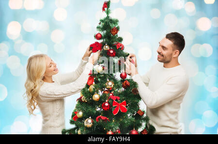 Heureux couple decorating Christmas Tree lights sur Banque D'Images