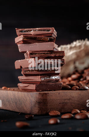 Des grains de café torréfiés et pile de chocolat sur le tableau noir. Banque D'Images