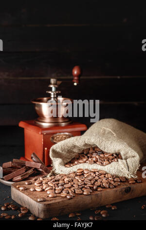 Still Life de grains de café dans des sacs de jute avec broyeur de café sur fond sombre. Copyspace sur le dessus. Banque D'Images