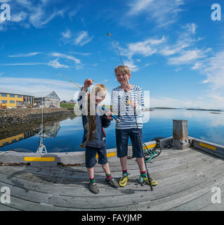 Les jeunes garçons brandissant une morue. La pêche au large de la jetée sur l'île de Flatey Breidafjordur, dans l'ouest de l'Islande Banque D'Images