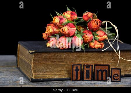 Bouquet de roses orange sur le vieux livre avec la typographie vintage carreaux. Banque D'Images