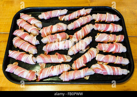 La nourriture de Noël traditionnel de saucisses enveloppées dans bacon, sur une plaque de cuisson pour l'Angleterre, Royaume-Uni Banque D'Images