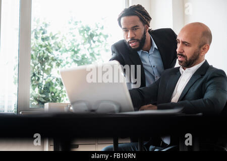 Deux hommes d'affaires travaillant avec un ordinateur portable par desk in office Banque D'Images