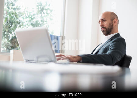 Businessman working concentré avec laptop at desk in office Banque D'Images