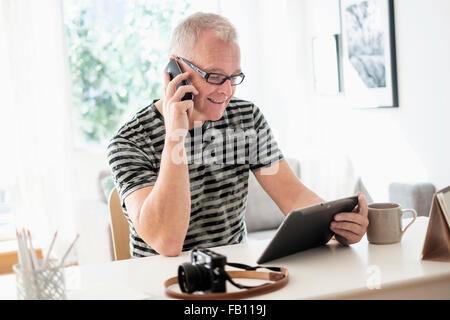 L'homme à l'aide de bureau à domicile tablette et smartphone Banque D'Images