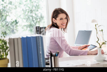 Young woman using digital tablet, looking at camera Banque D'Images