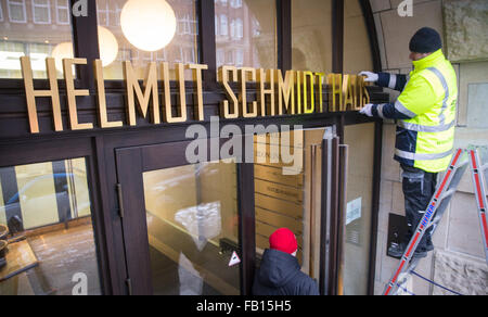 Hambourg, Allemagne. Jan 7, 2016. Un homme définit la nouvelle 'lettrage Helmut-Schmidt-Haus' sur l'entrée de l'immeuble anciennement connu sous le nom de 'Pressehaus' dans le centre de Hambourg, Allemagne, 7 janvier 2016. La maison d'édition de l'hebdomadaire Die Zeit est en train de changer son nom en l'honneur de l'éditeur de longue date et l'ancien chancelier allemand Helmut Schmidt (1918-2015). PHOTO : CHRISTIAN CHARISIUS/DPA/Alamy Live News Banque D'Images